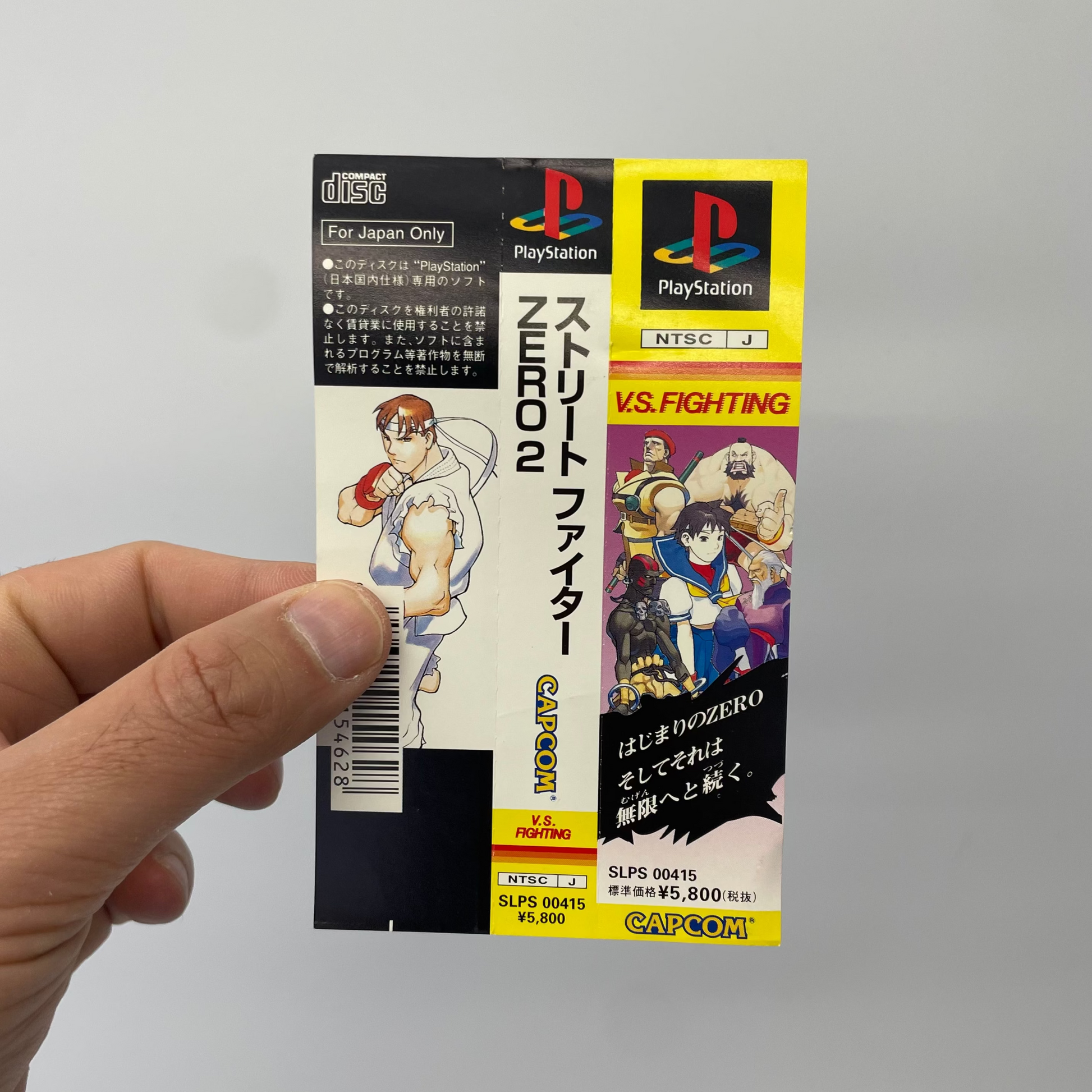 PlayStation game cartridge held by a hand with a gray background