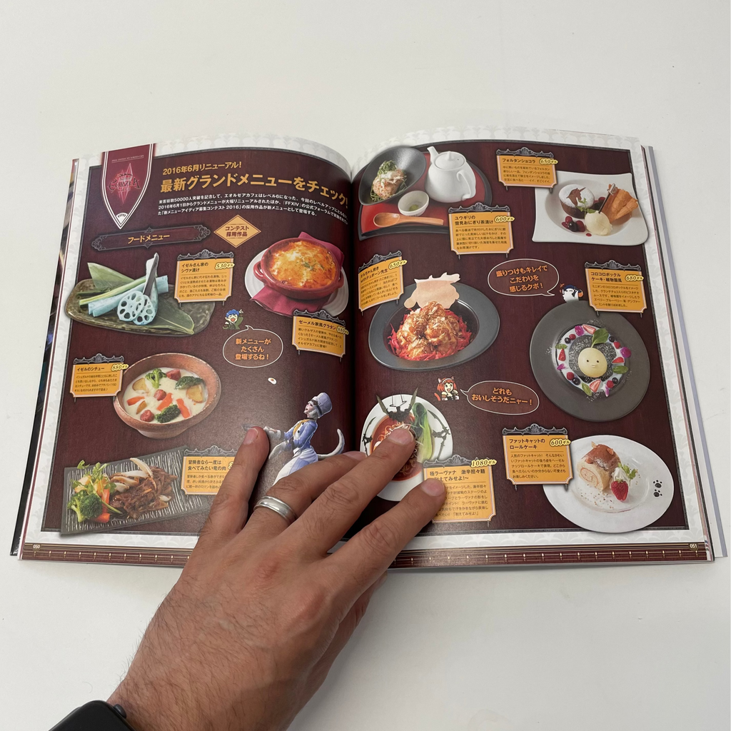 Open book with food menu pages and a hand holding it on a white surface