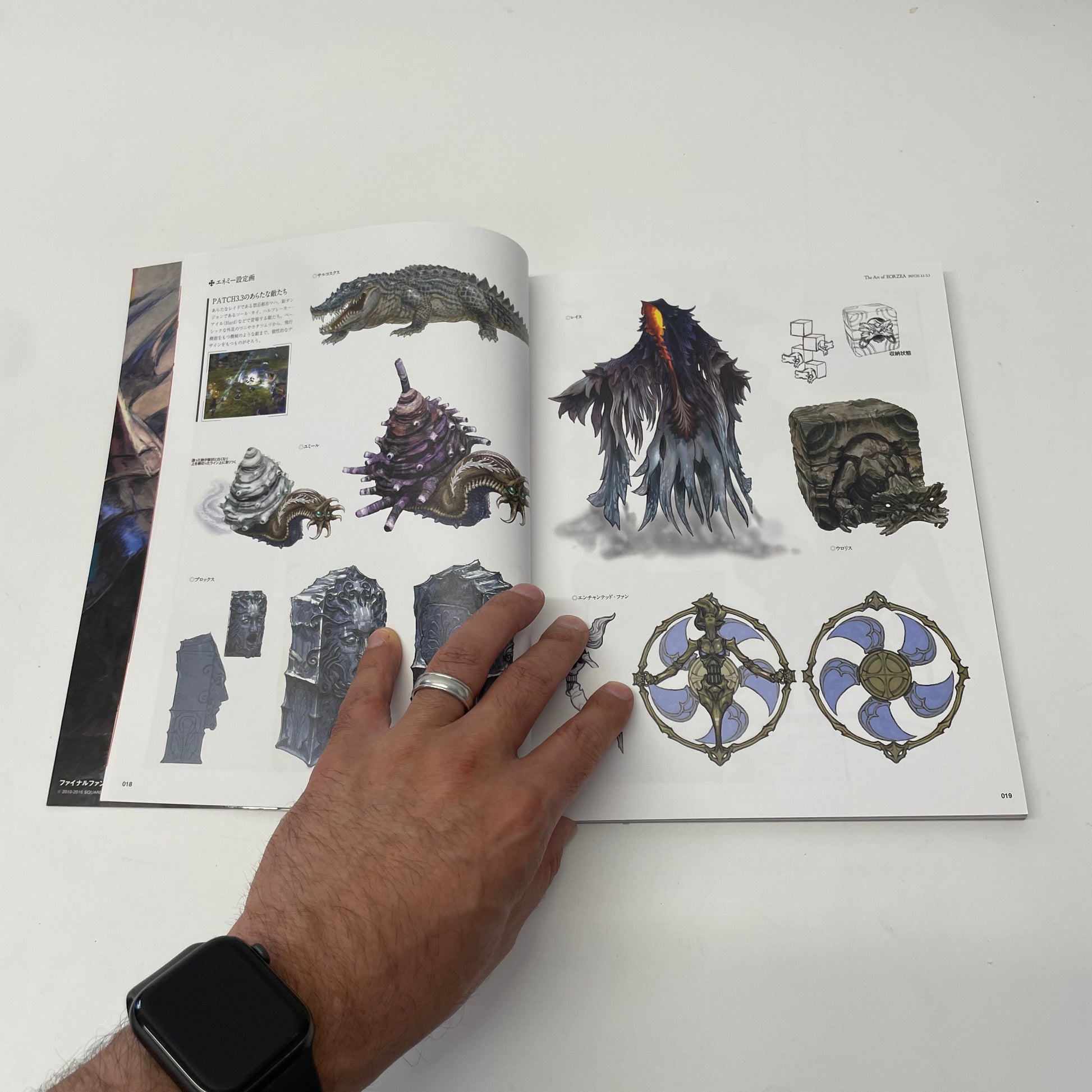 Open book with illustrations of fantasy creatures and designs, held open by a hand.