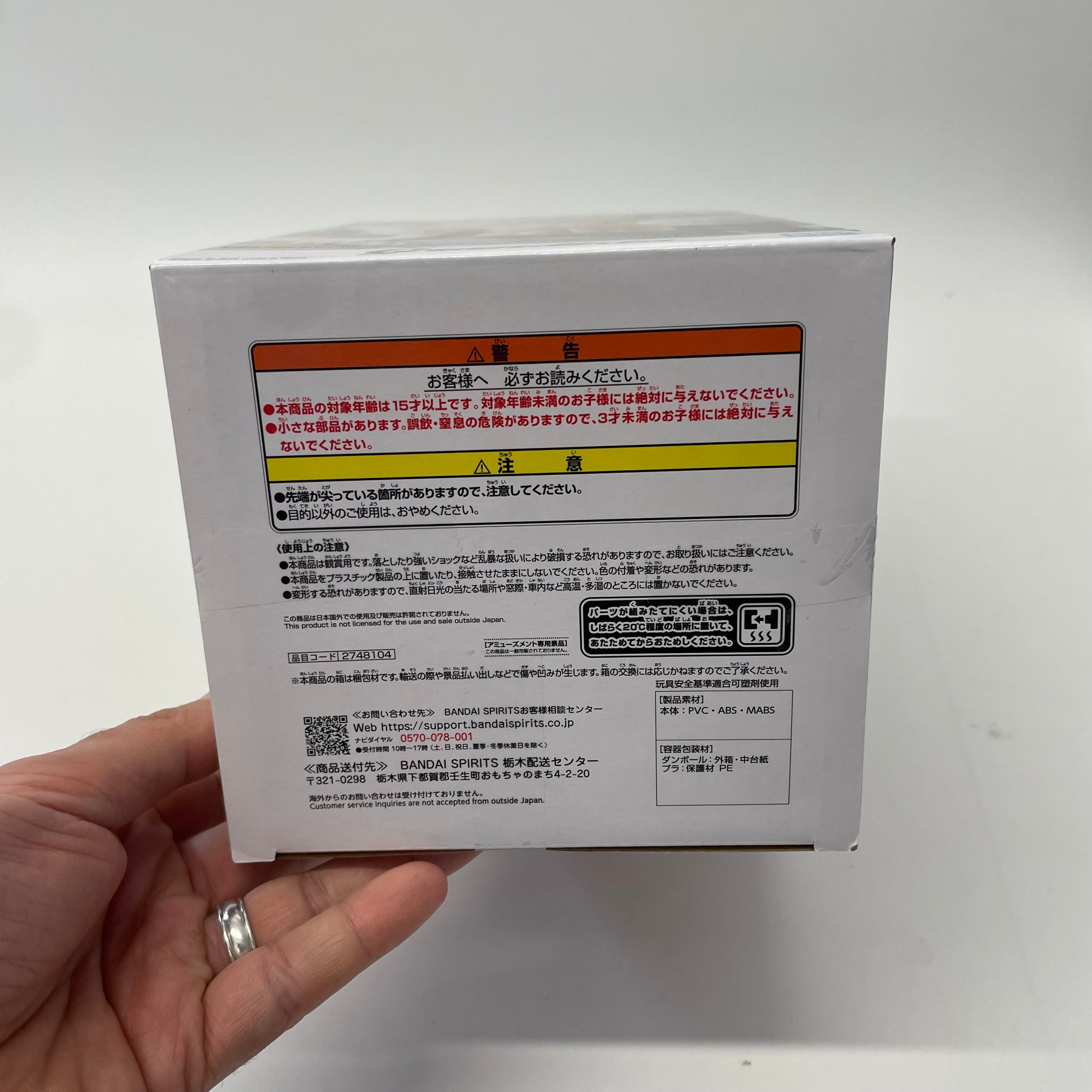 Hand holding a white box with text and a QR code on a white background