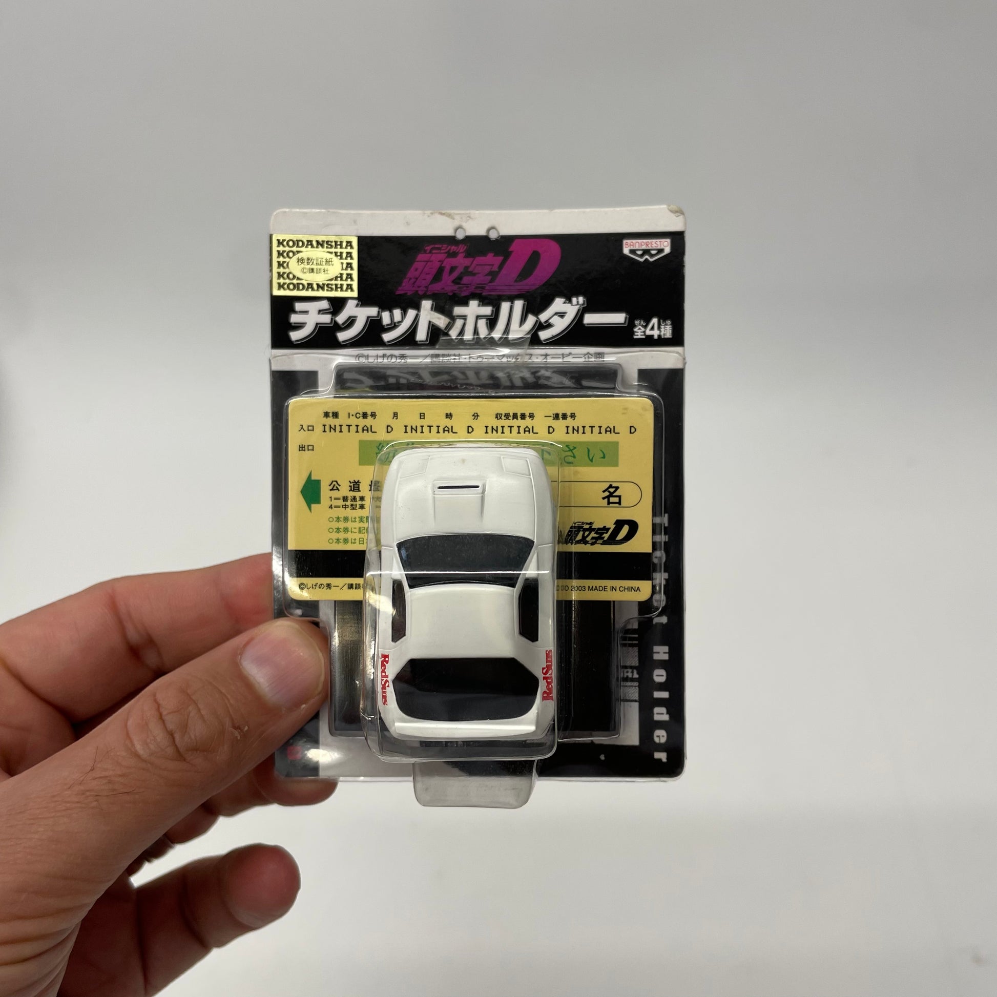 Model car in packaging held by a hand on a gray background