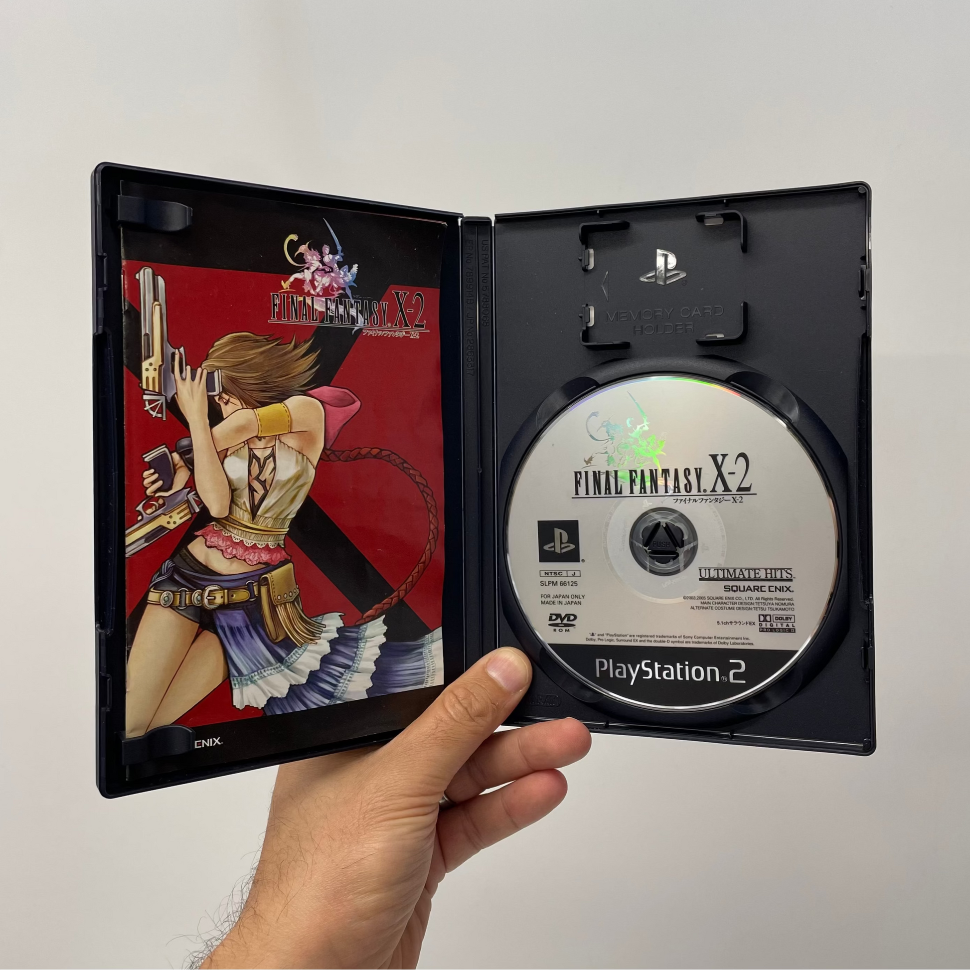 PlayStation 2 game case for 'Final Fantasy X-2' held by a hand against a plain background