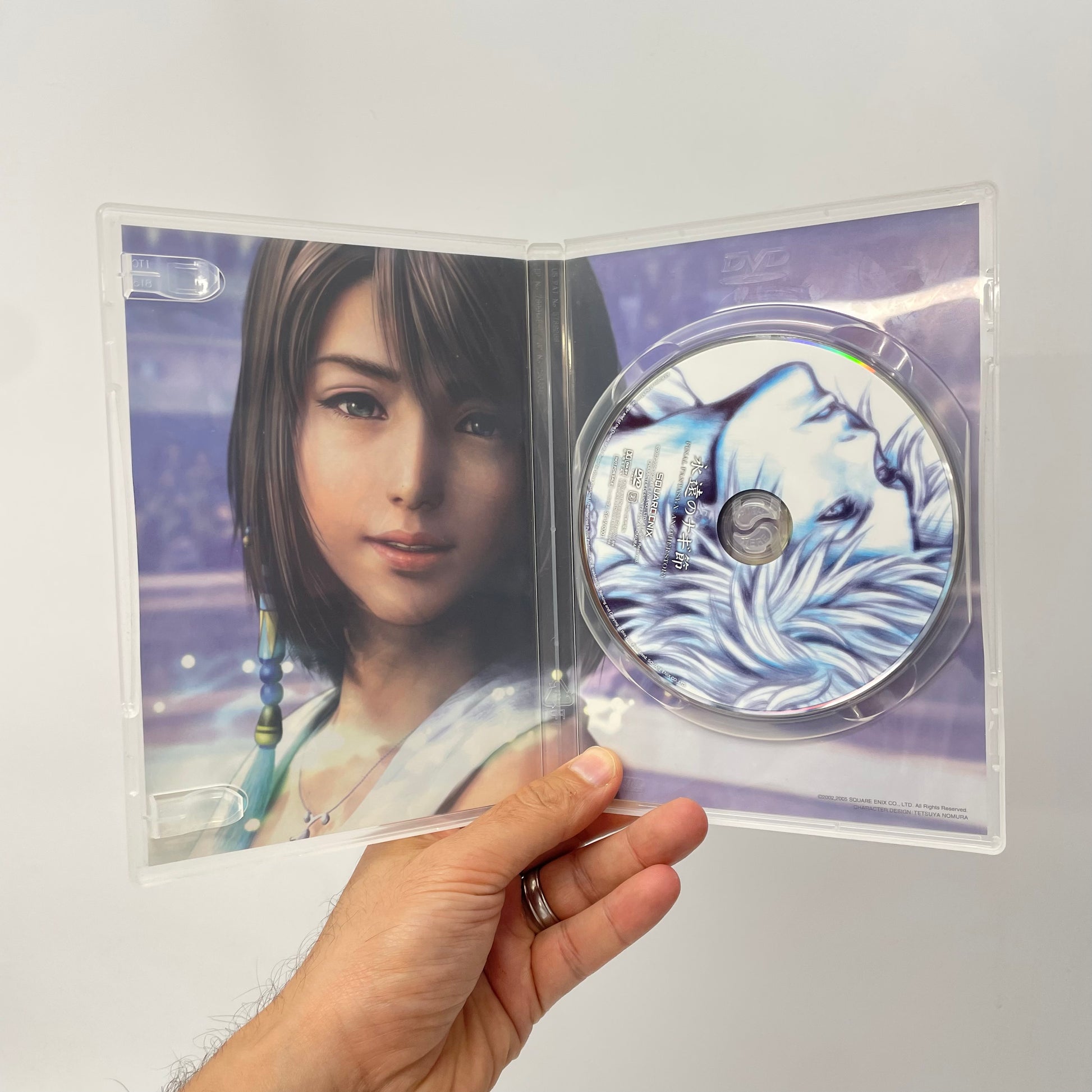 Hand holding a transparent DVD case with an image of a woman and a wolf design on a white background