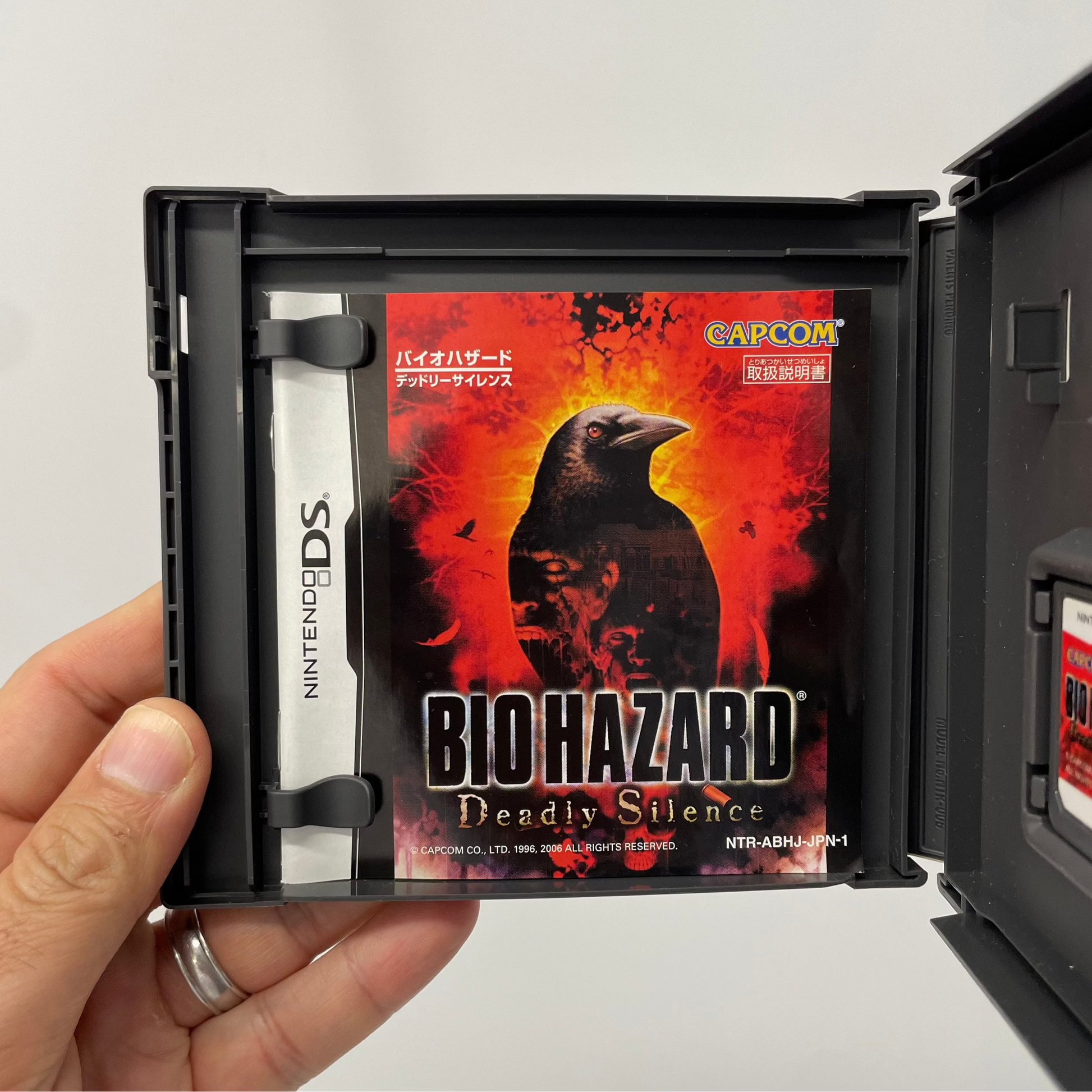 Nintendo DS game case titled 'Biohazard: Deadly Silence' held by a hand.