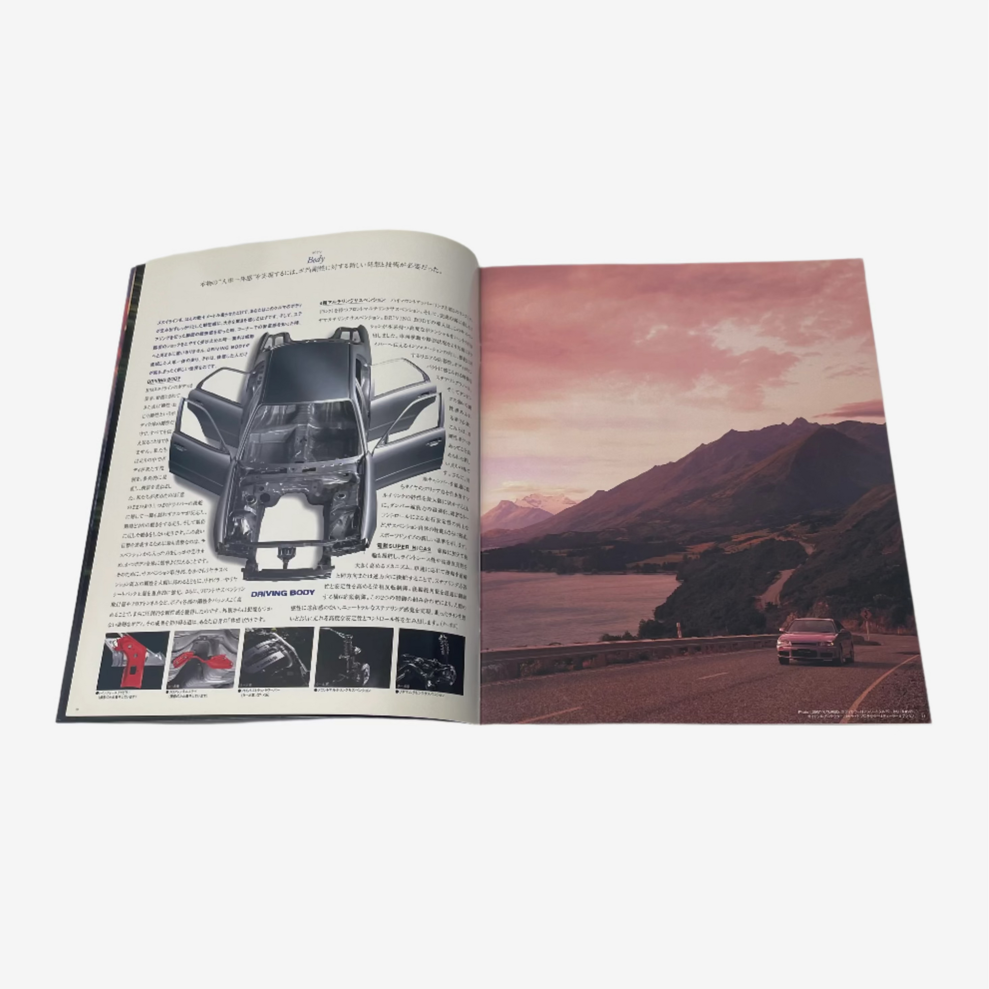 Open book showing a car interior diagram on one page and a scenic road with mountains on the other, on a white background.