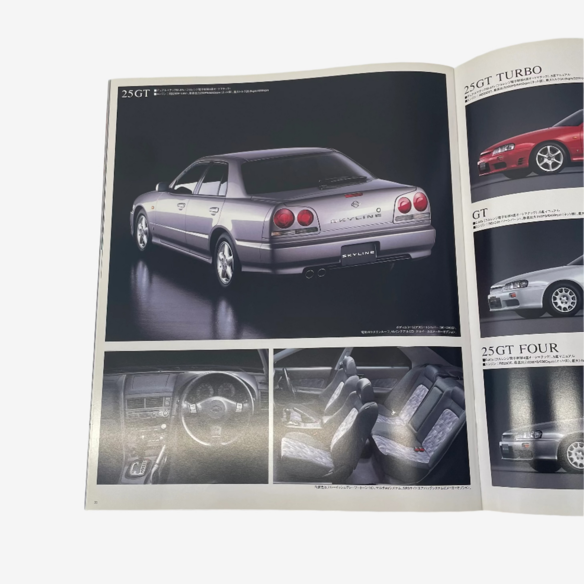 Open magazine or book showing car advertisements with a focus on a silver sedan.