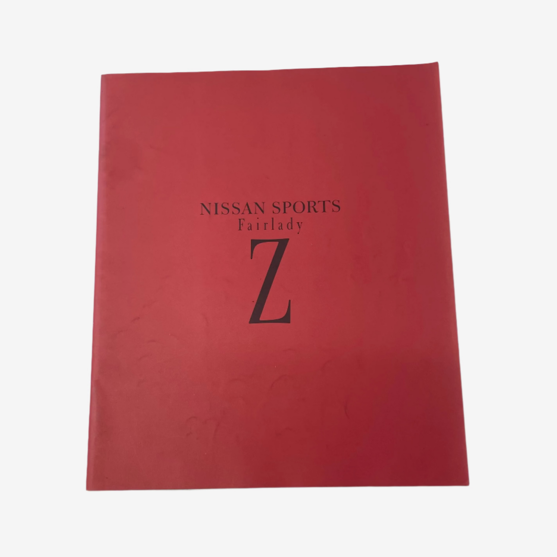Red book or folder with 'Nissan Sports Fairlady Z' text on a white background