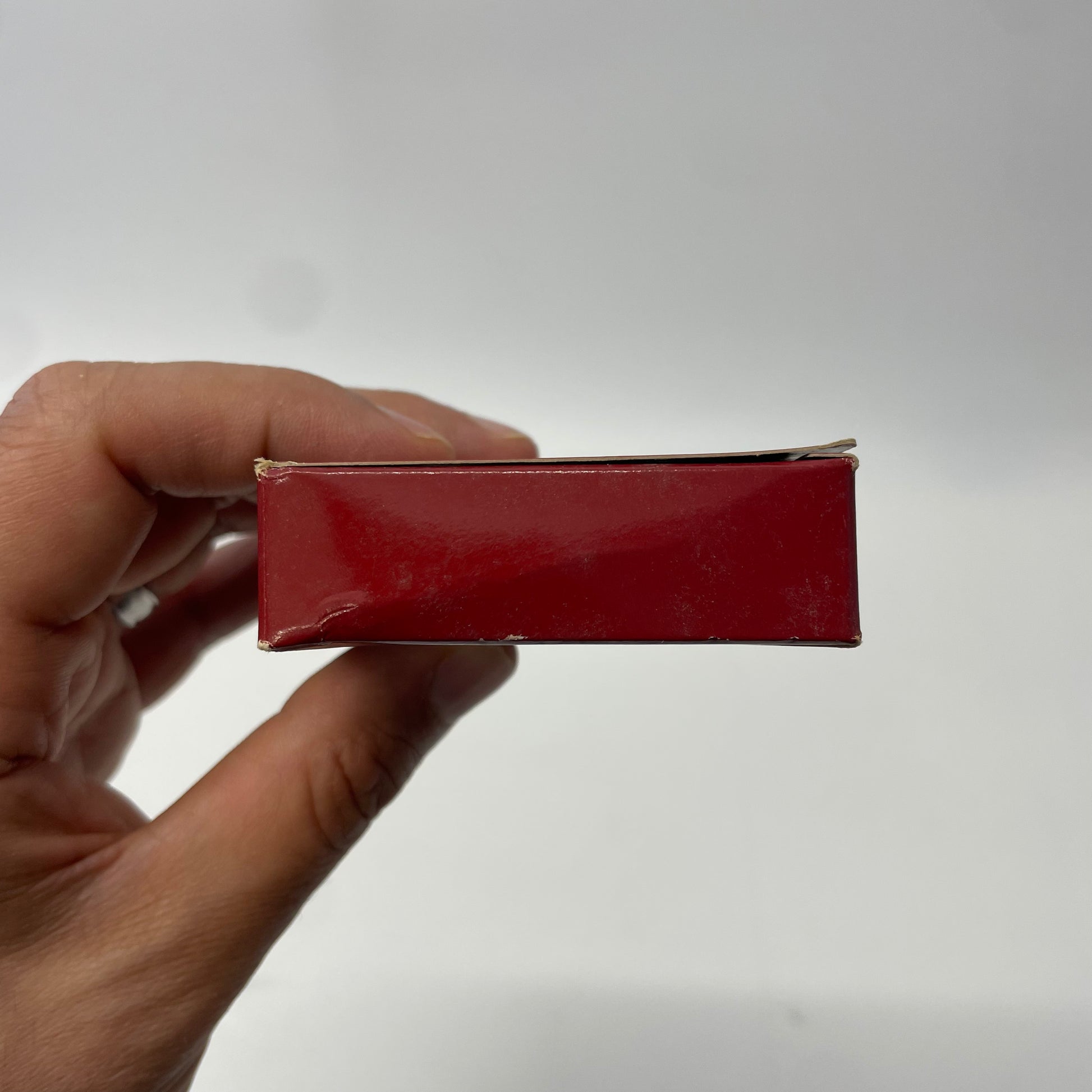 Hand holding a red rectangular object against a white background