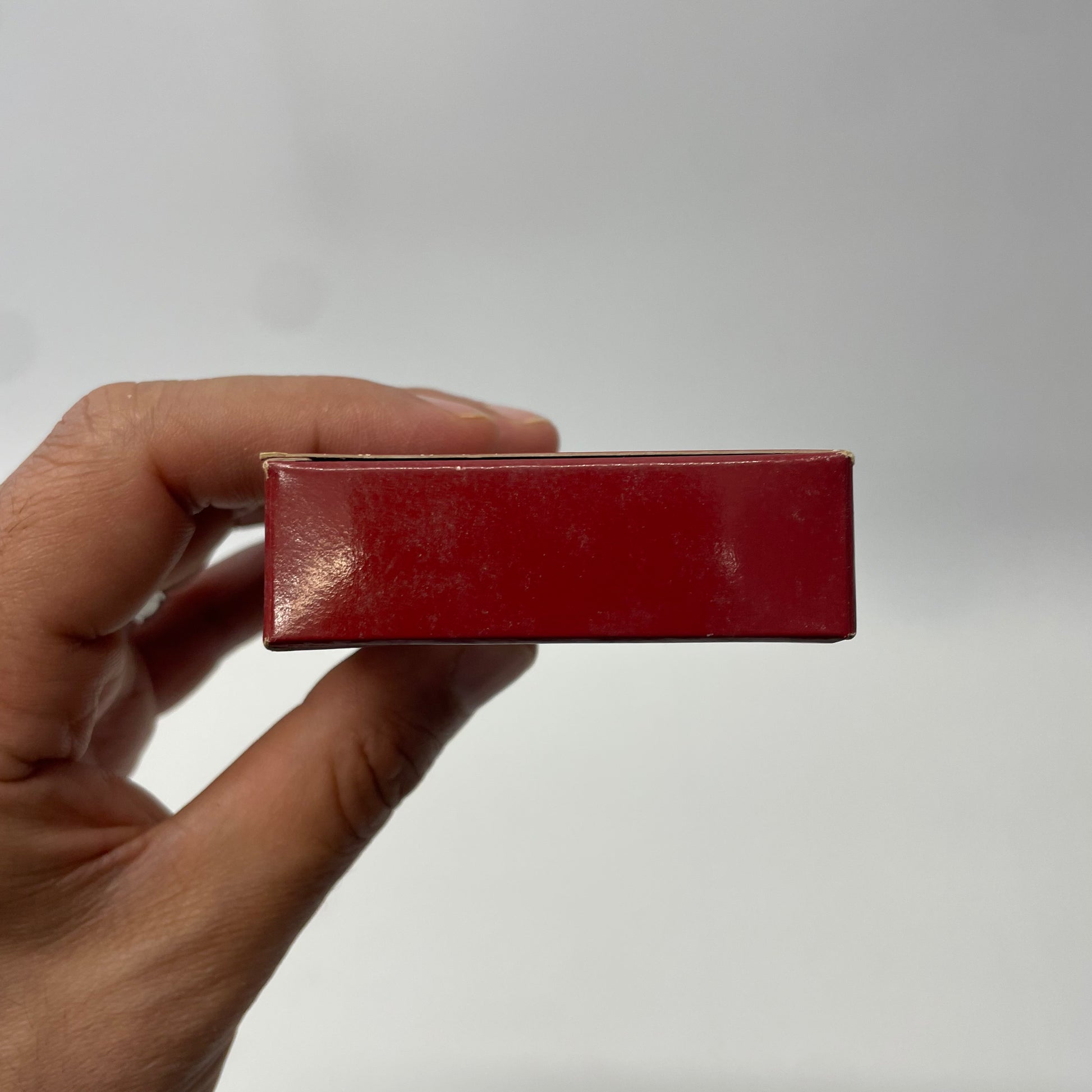 Hand holding a red rectangular object against a plain background