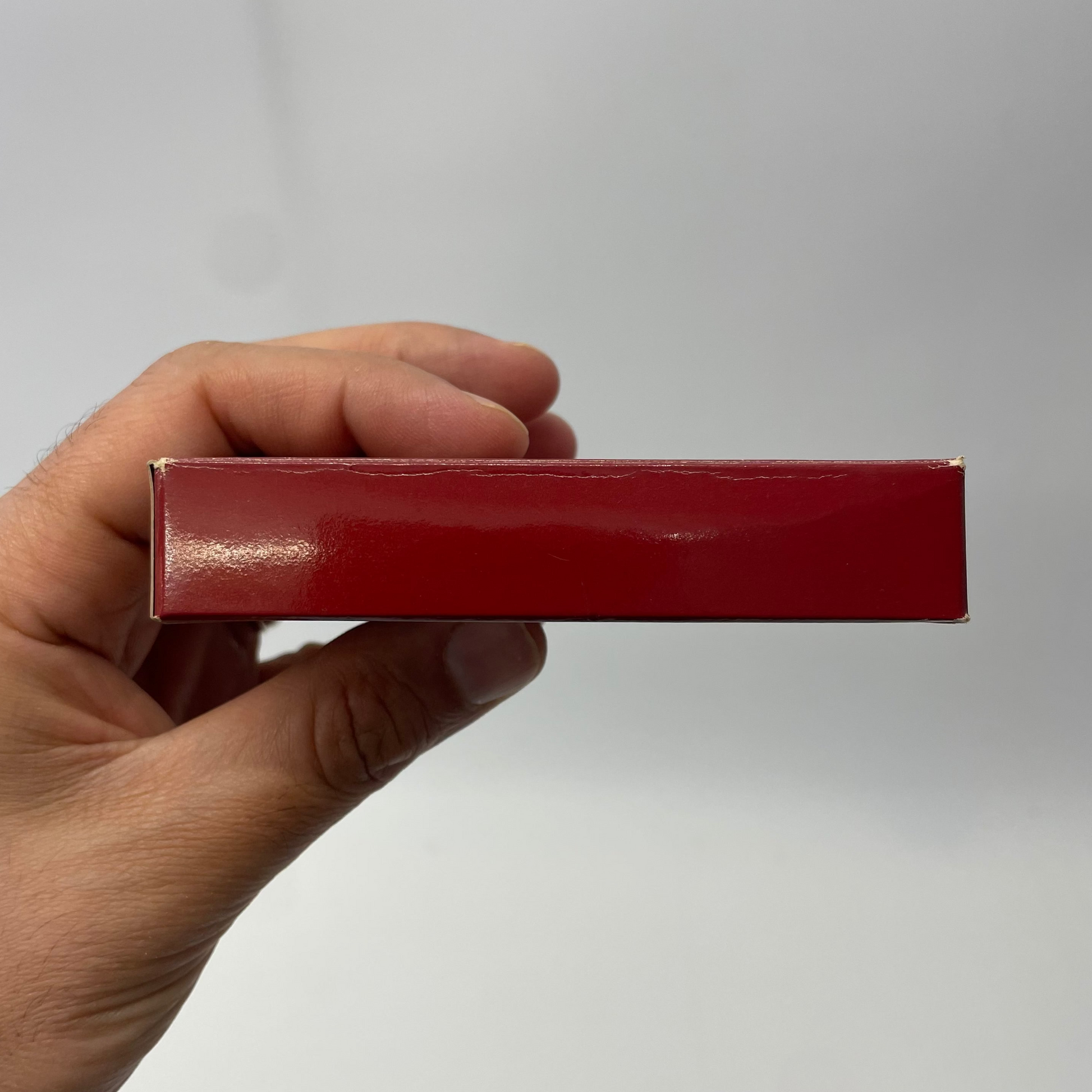 Hand holding a red rectangular object against a plain background