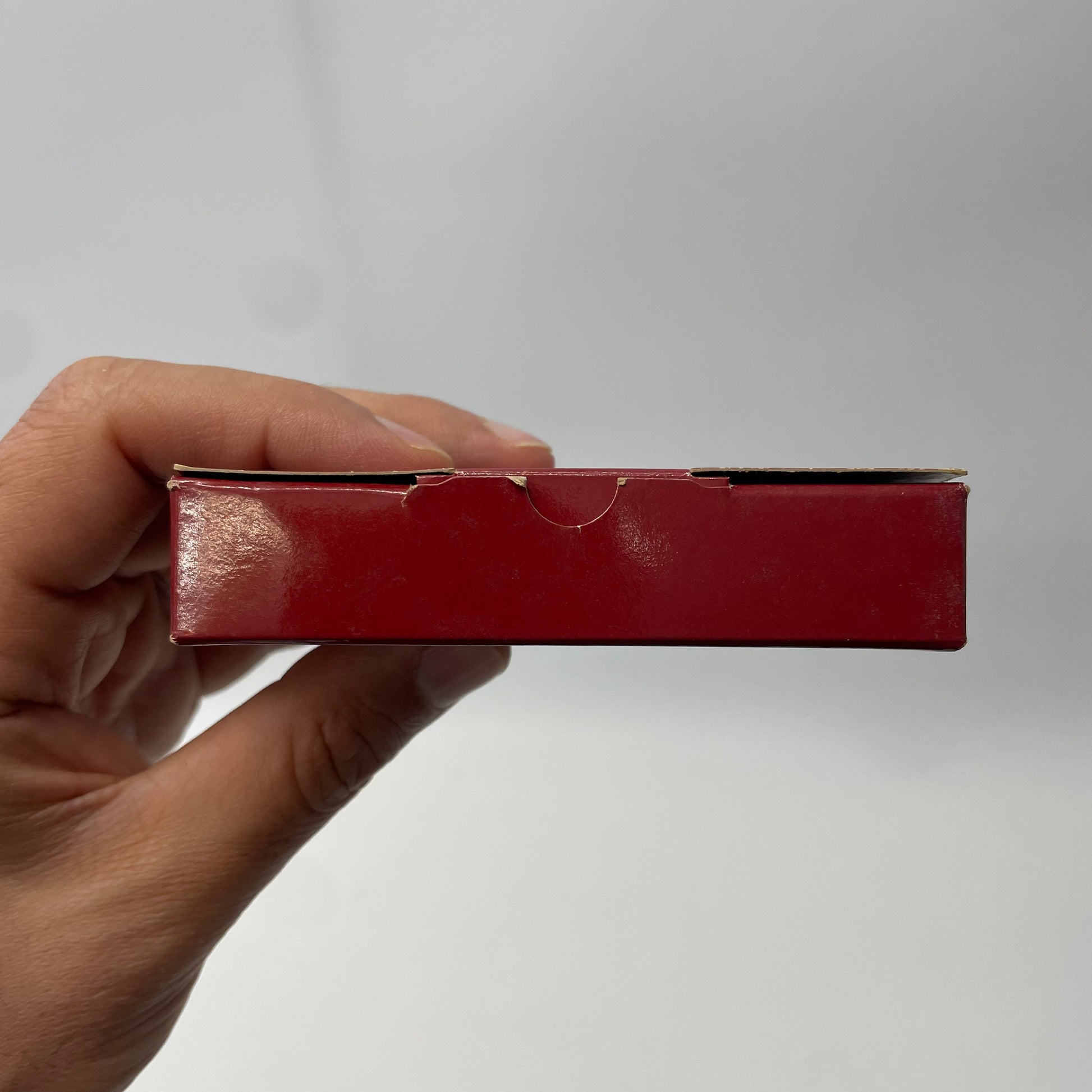 Hand holding a red rectangular object against a plain background