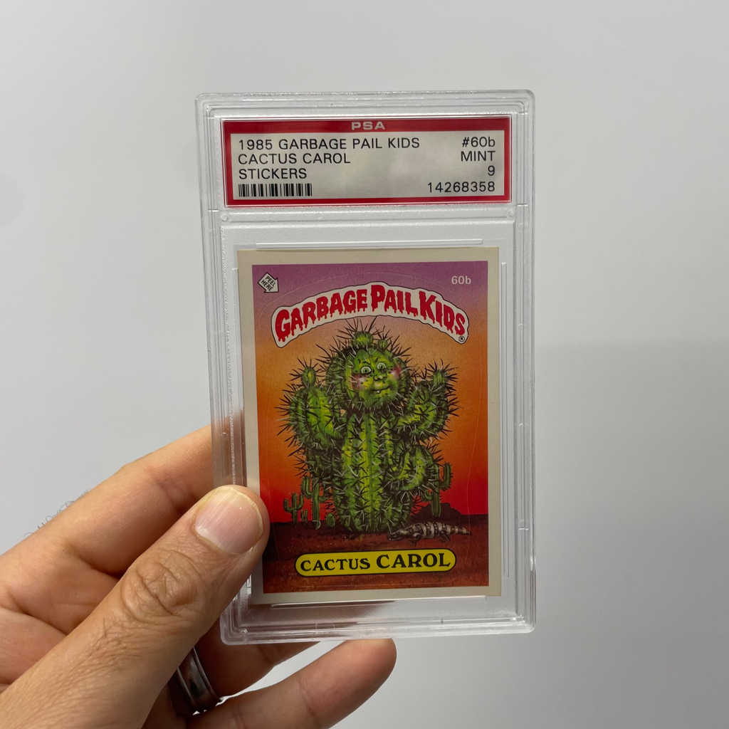 Garbage Pail Kids card featuring Cactus Carol held by a hand on a gray background