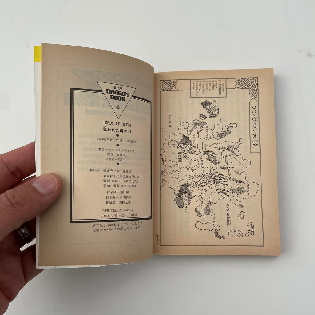 Open book with text and map on beige pages, held by a hand against a white background