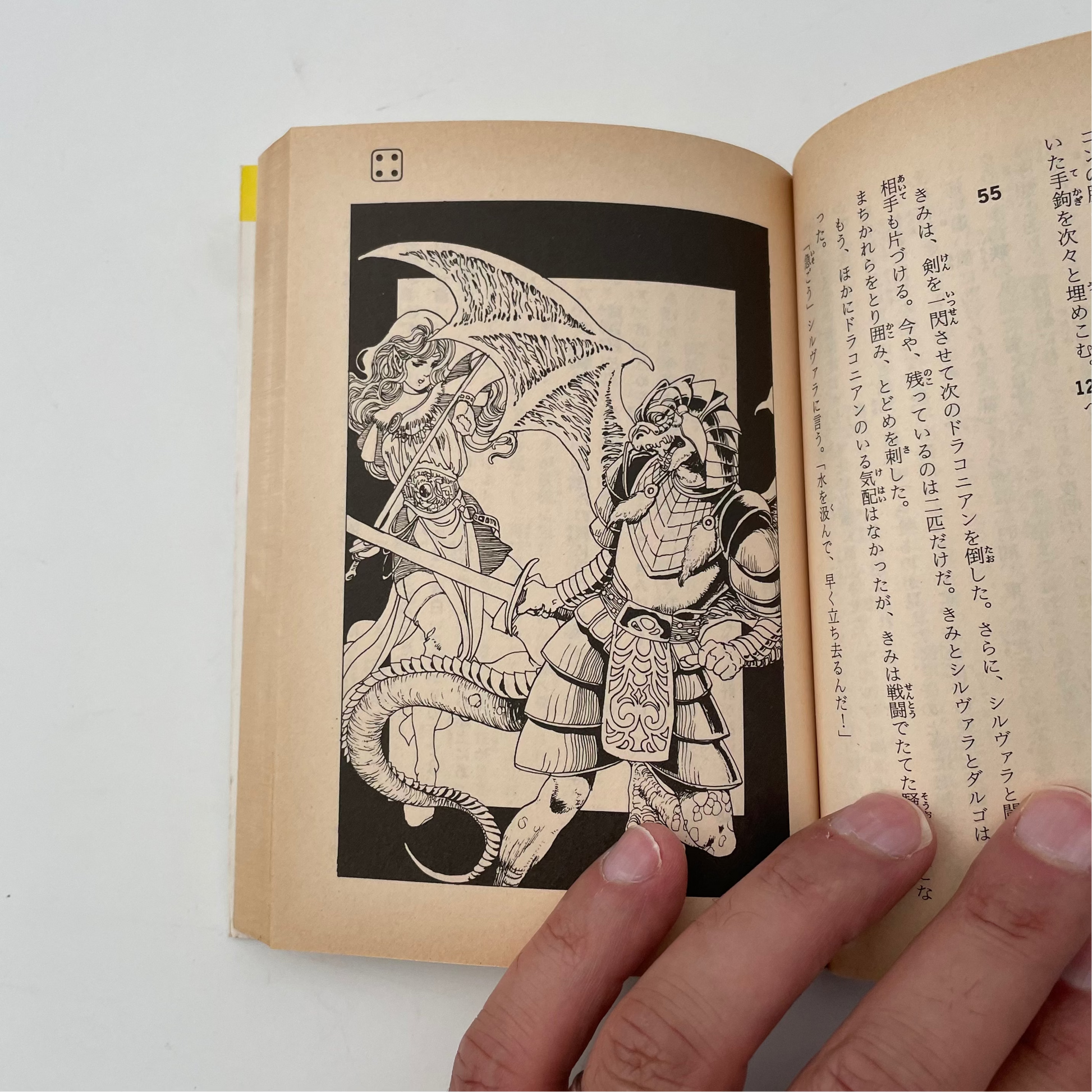 Open book with a black and white illustration of a warrior and dragon on a white background