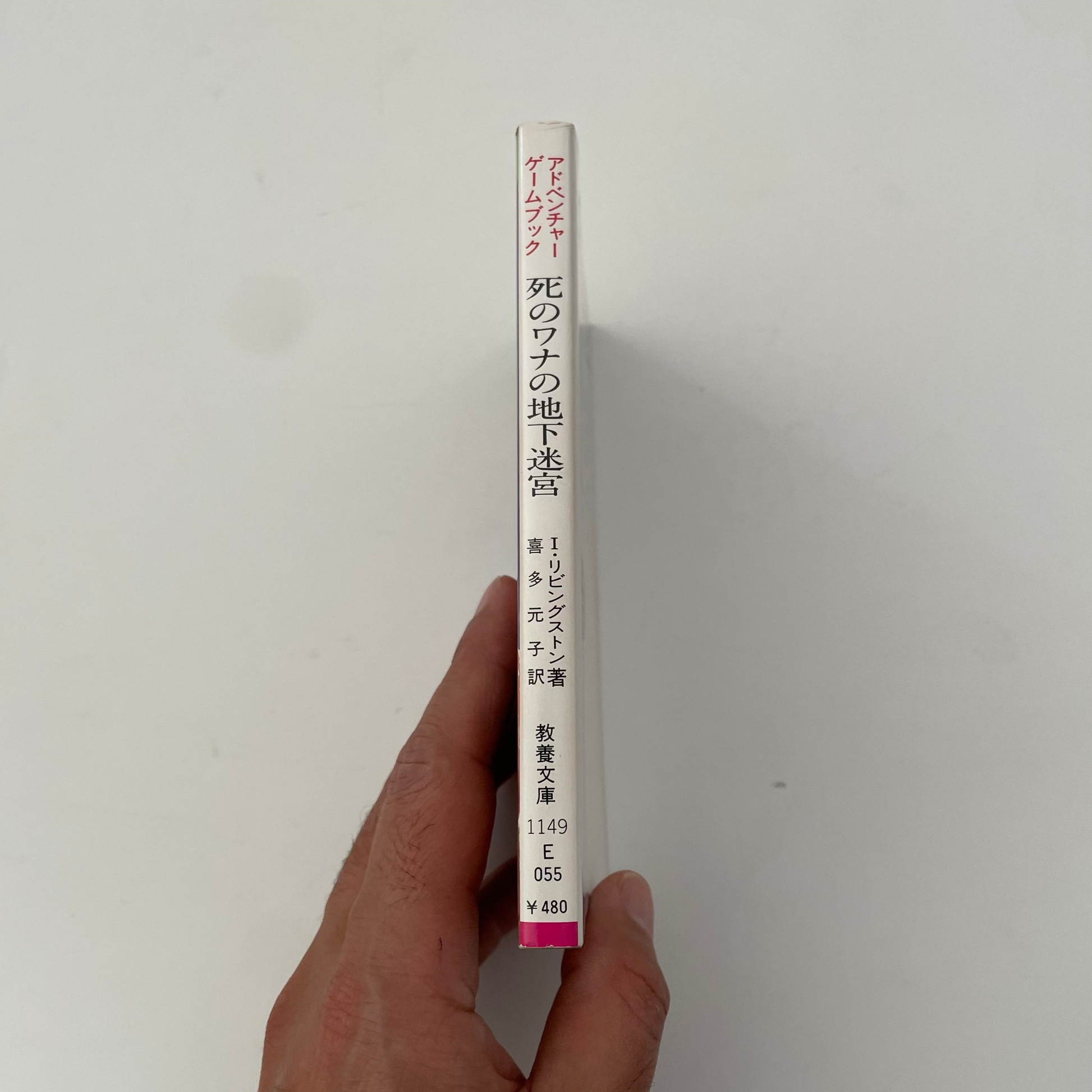 Hand holding a cylindrical tube with text on a plain background