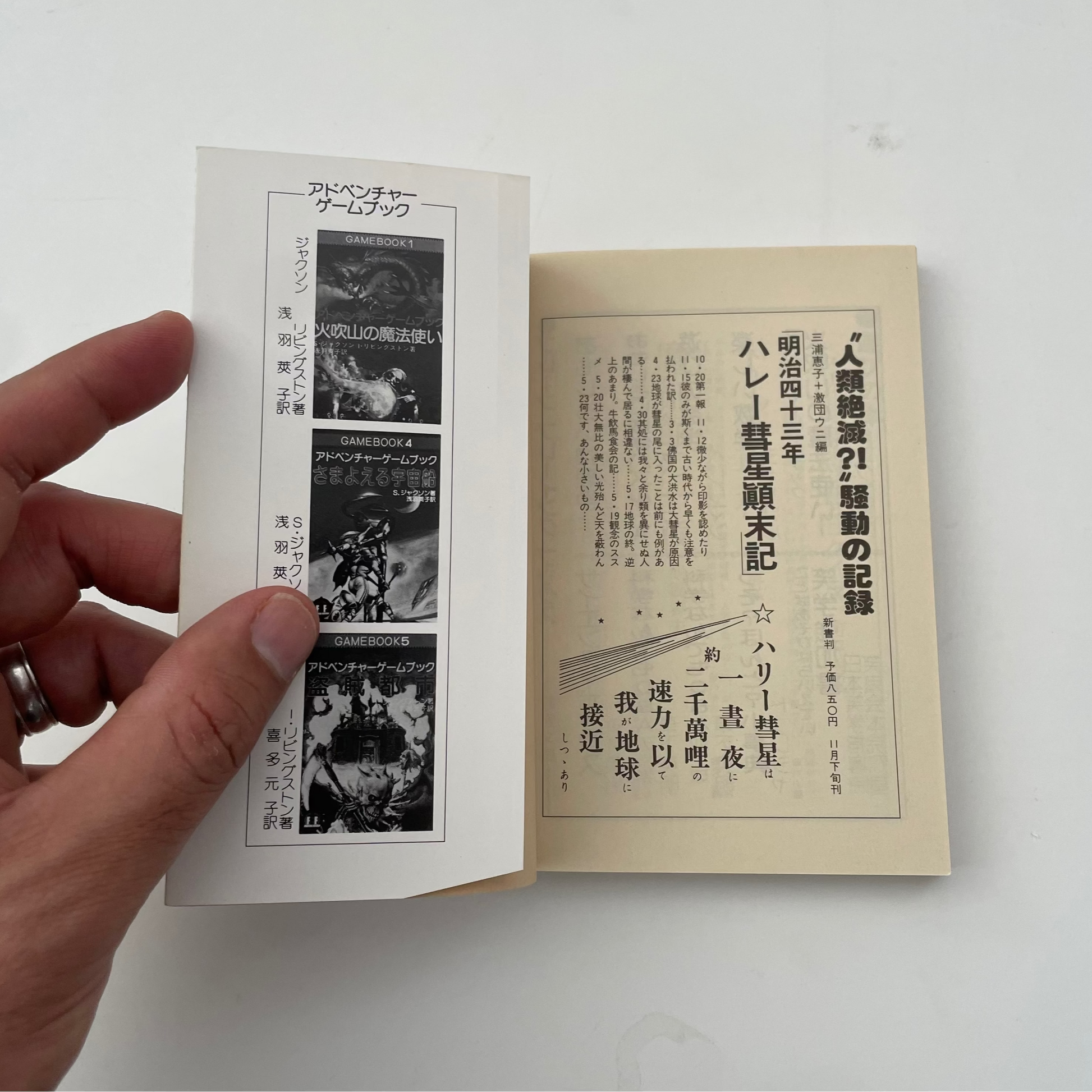 Hand holding an open book with black and white illustrations and text on a light background