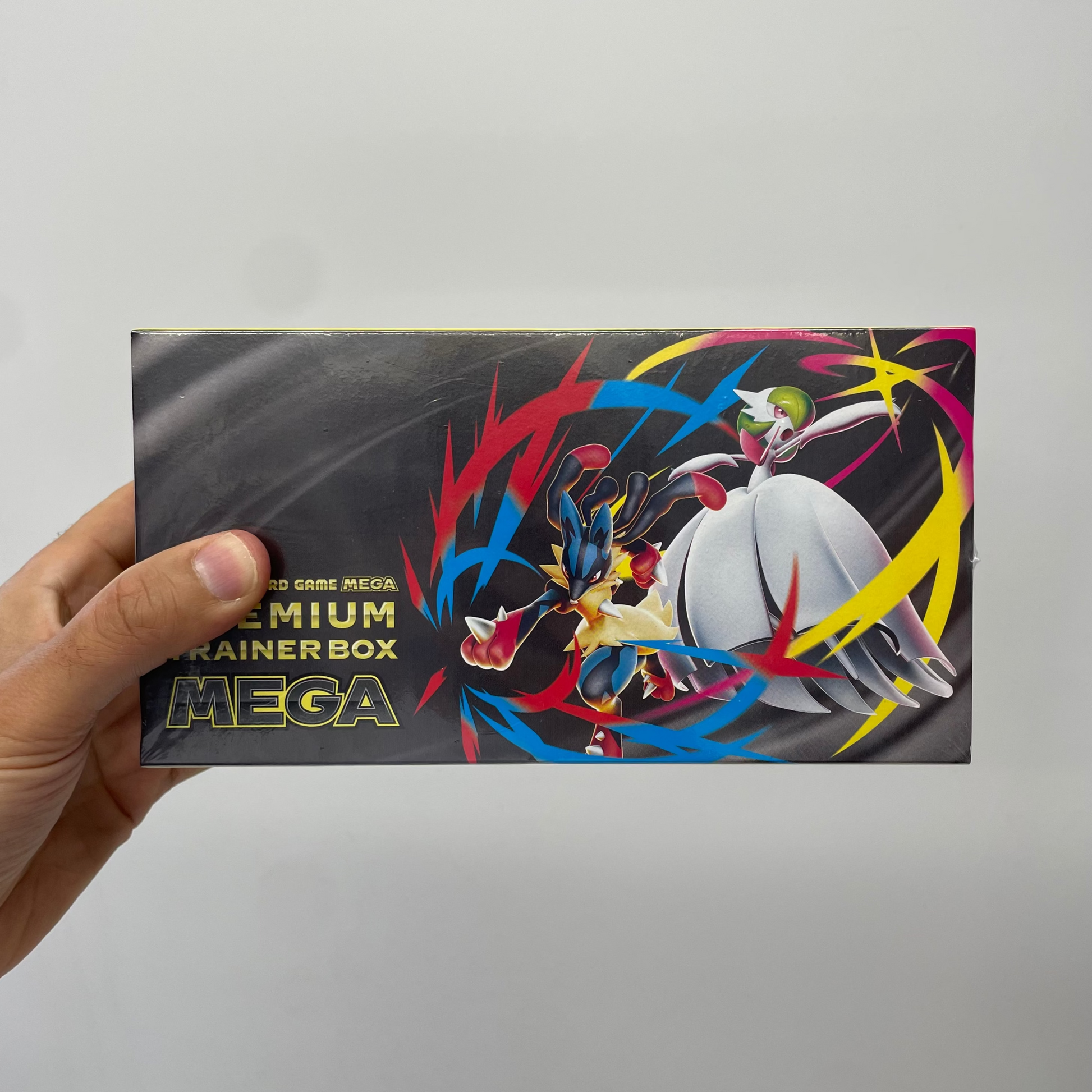 Hand holding a Pokémon trading card game Mega Premium Trainer Box against a gray background