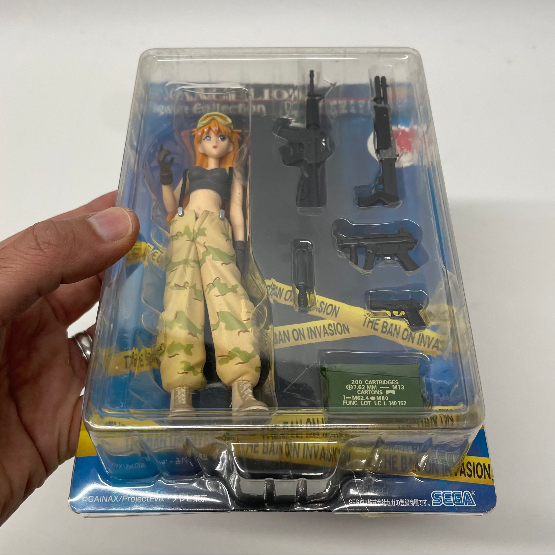Toy figure in packaging held by a hand on a white background