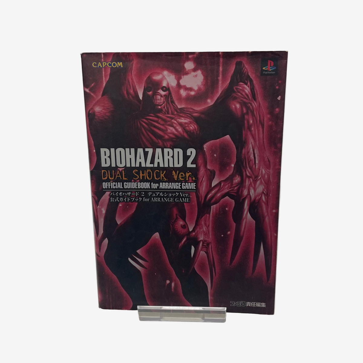Biohazard 2 Dual Shock Ver. official guidebook on a stand with Capcom logo.