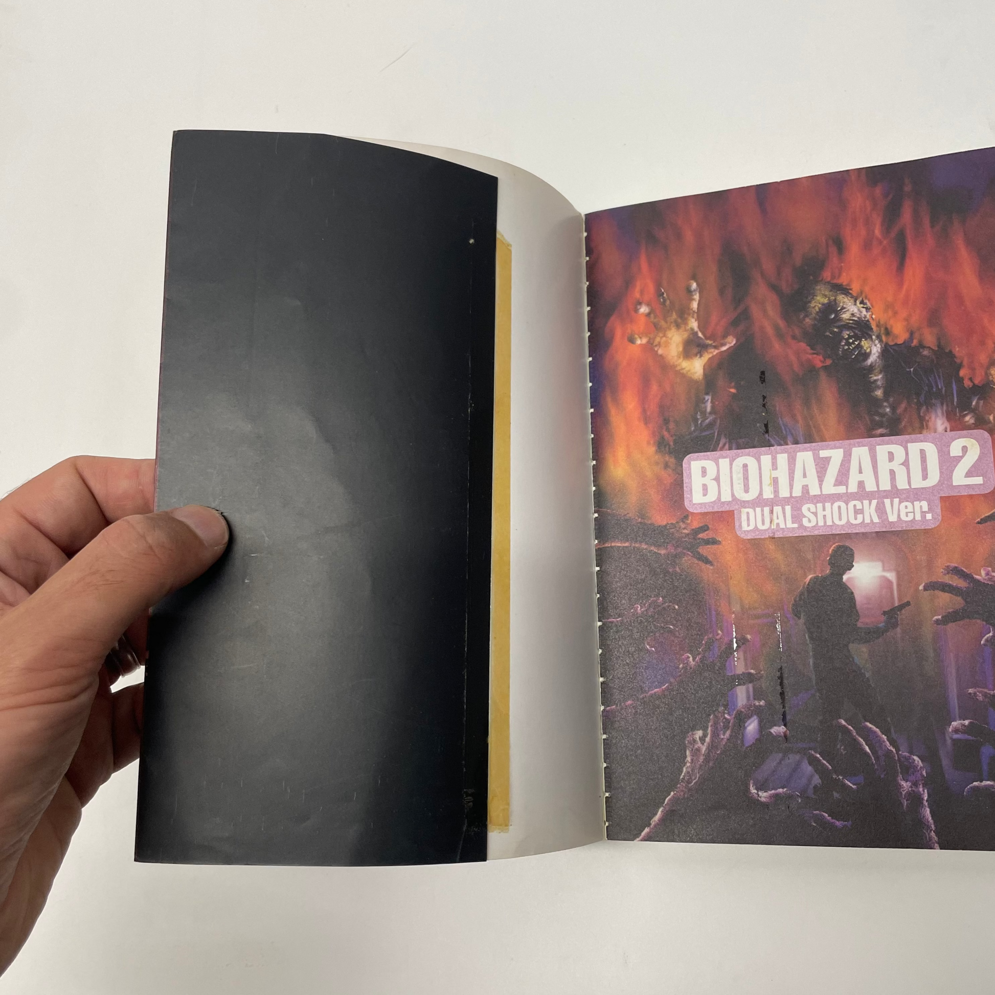 Open book with a cover featuring 'Biohazard 2' artwork on a white background