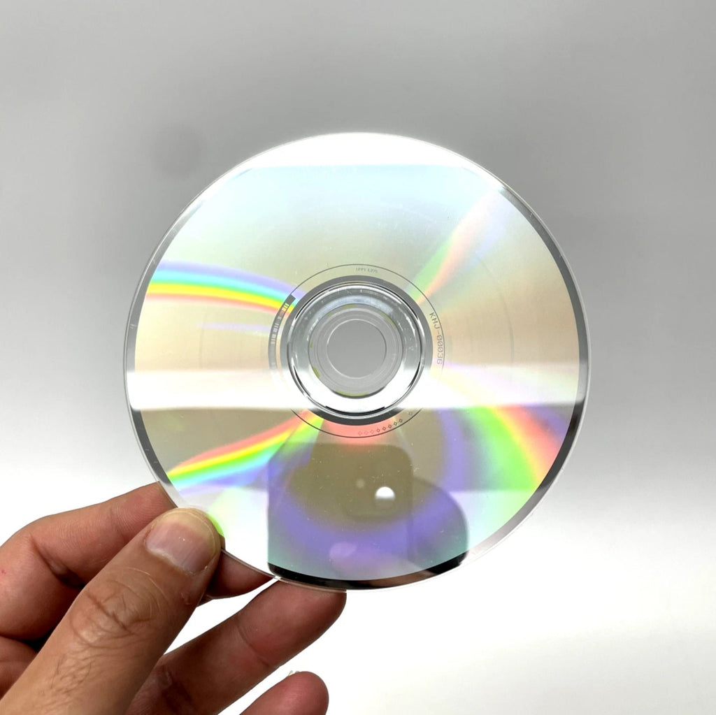 Hand holding a CD with rainbow reflection against a gray background