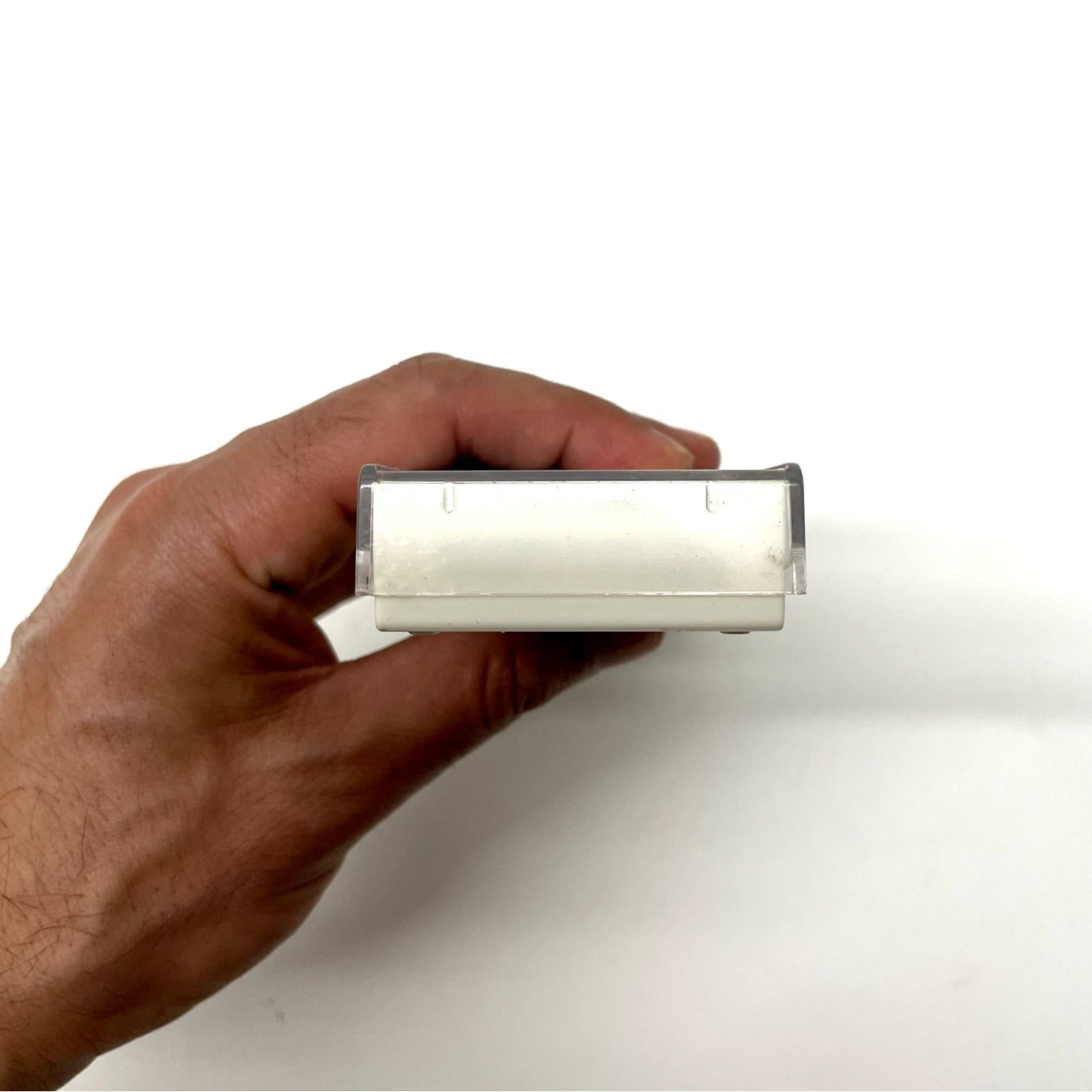 Hand holding a rectangular object against a white background