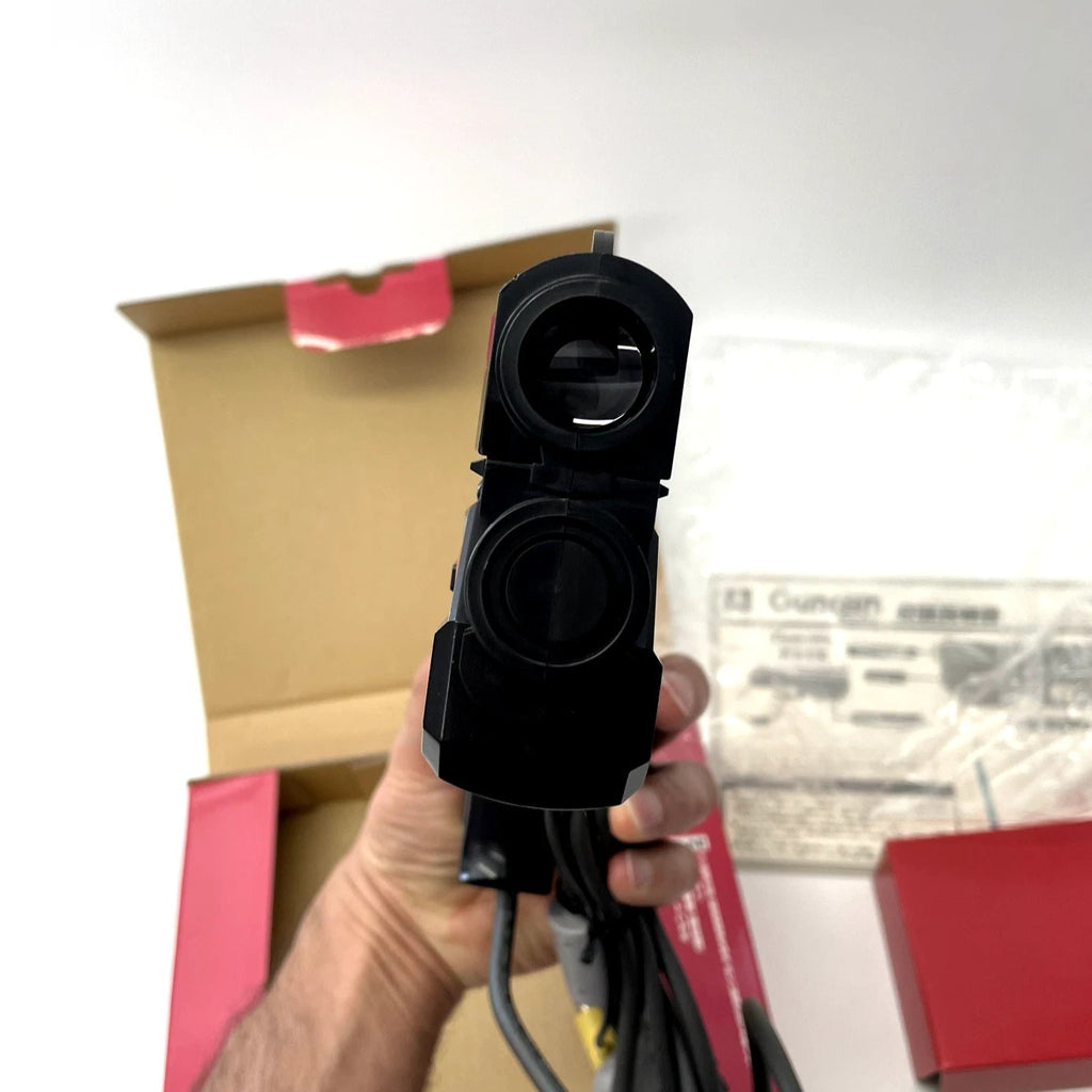 Person holding a black electronic device with wires against a blurred indoor background