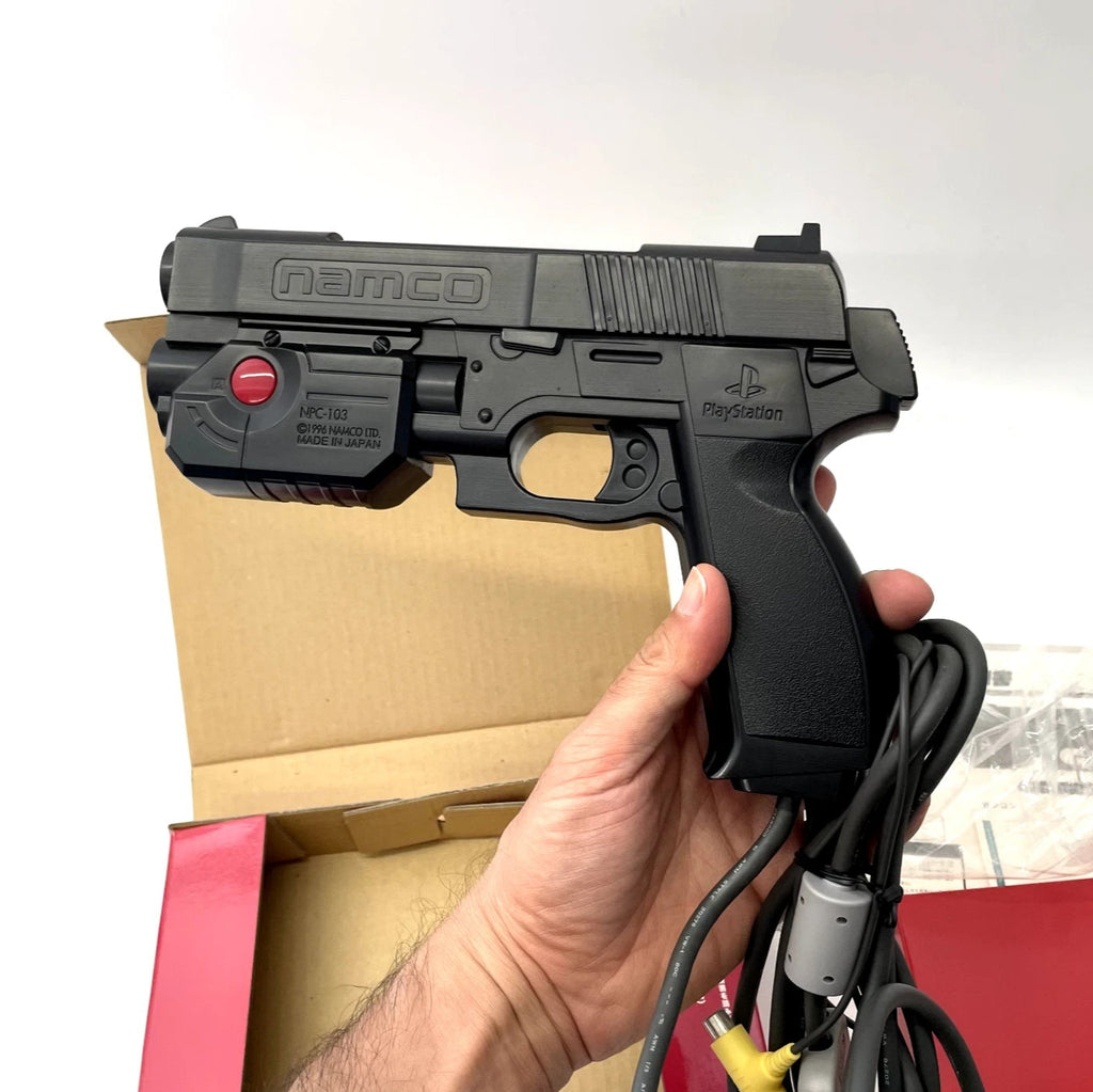Black toy gun with 'Namco' branding held by a hand against a white background