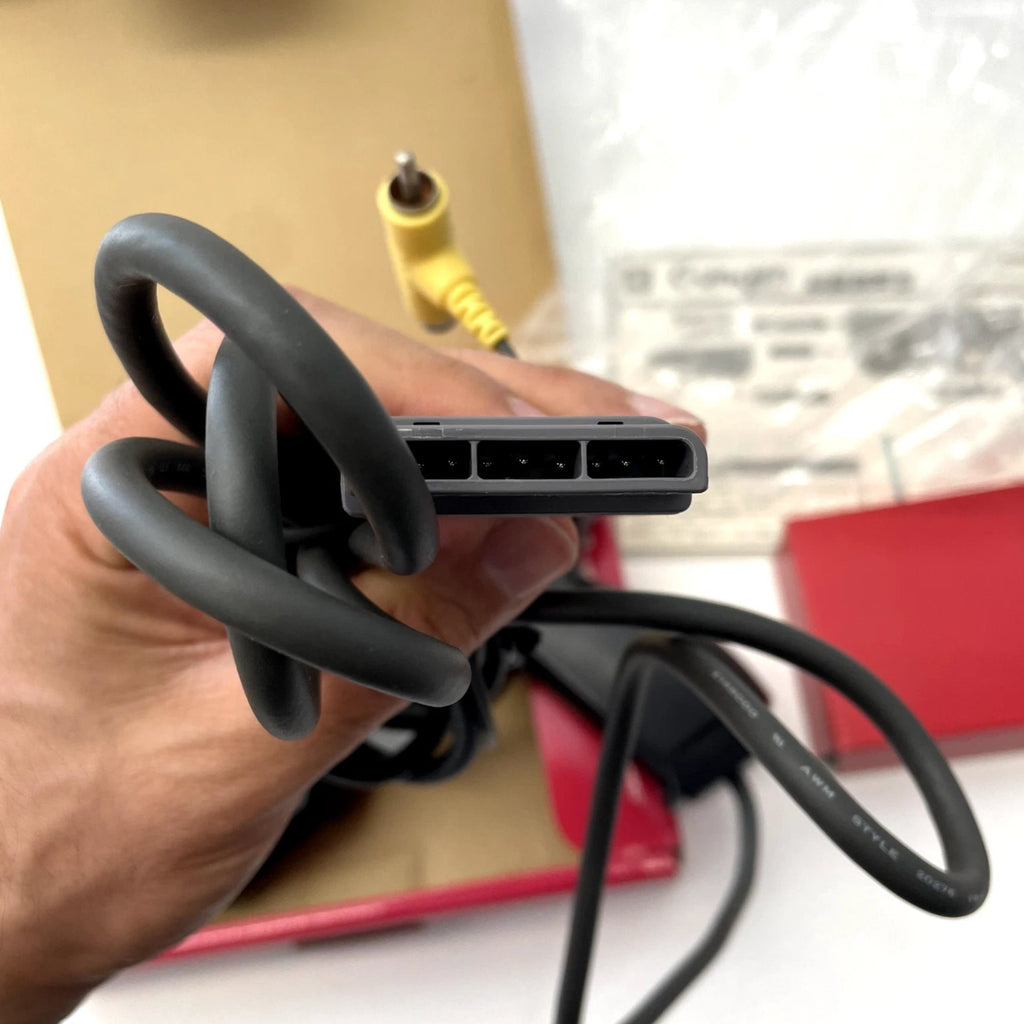 Hand holding a coiled black cable with connectors, blurred background