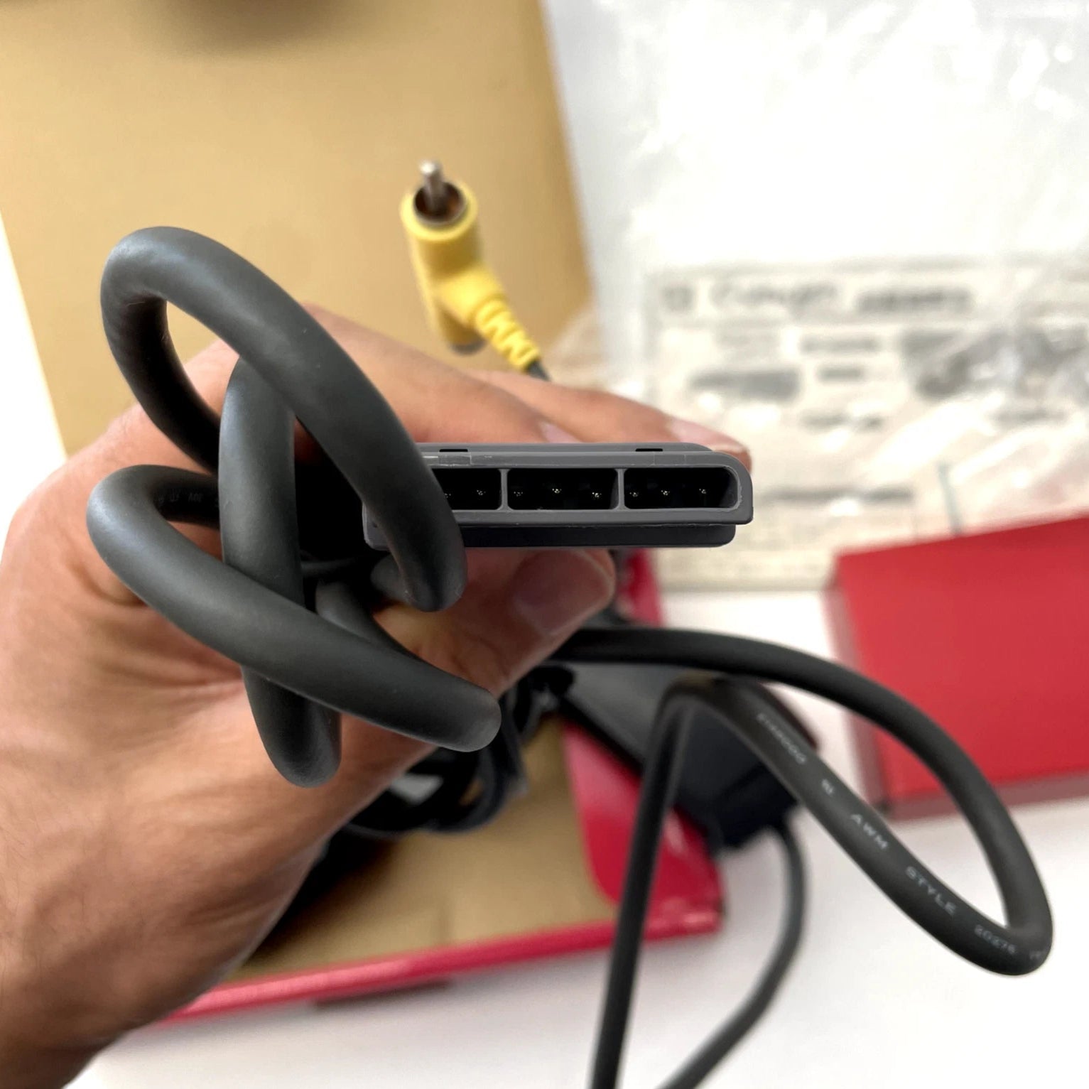 Hand holding a coiled black cable with connectors, blurred background