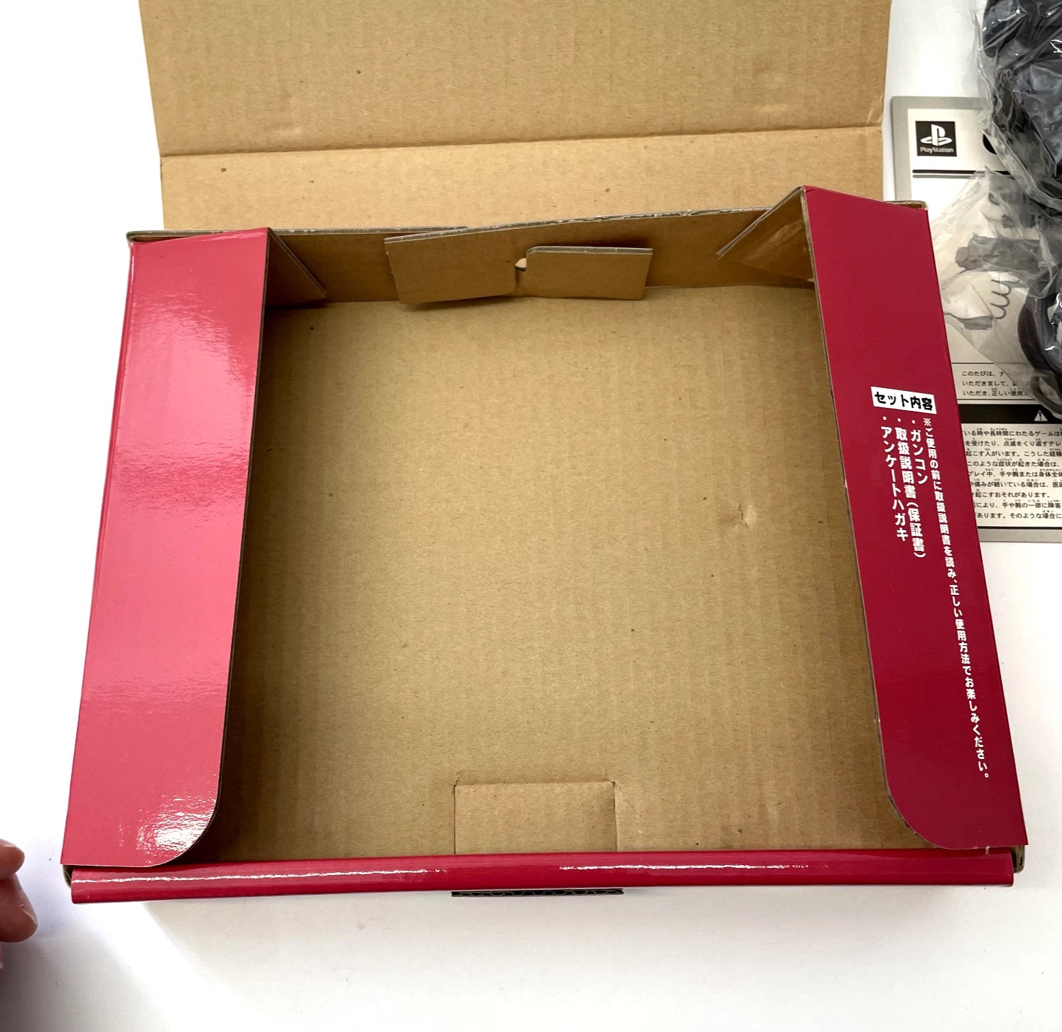Open cardboard box with red interior on a white surface