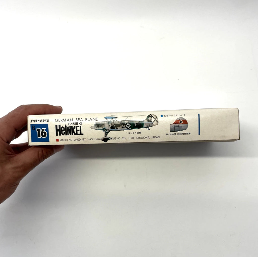 Model airplane kit box held by a hand on a white background