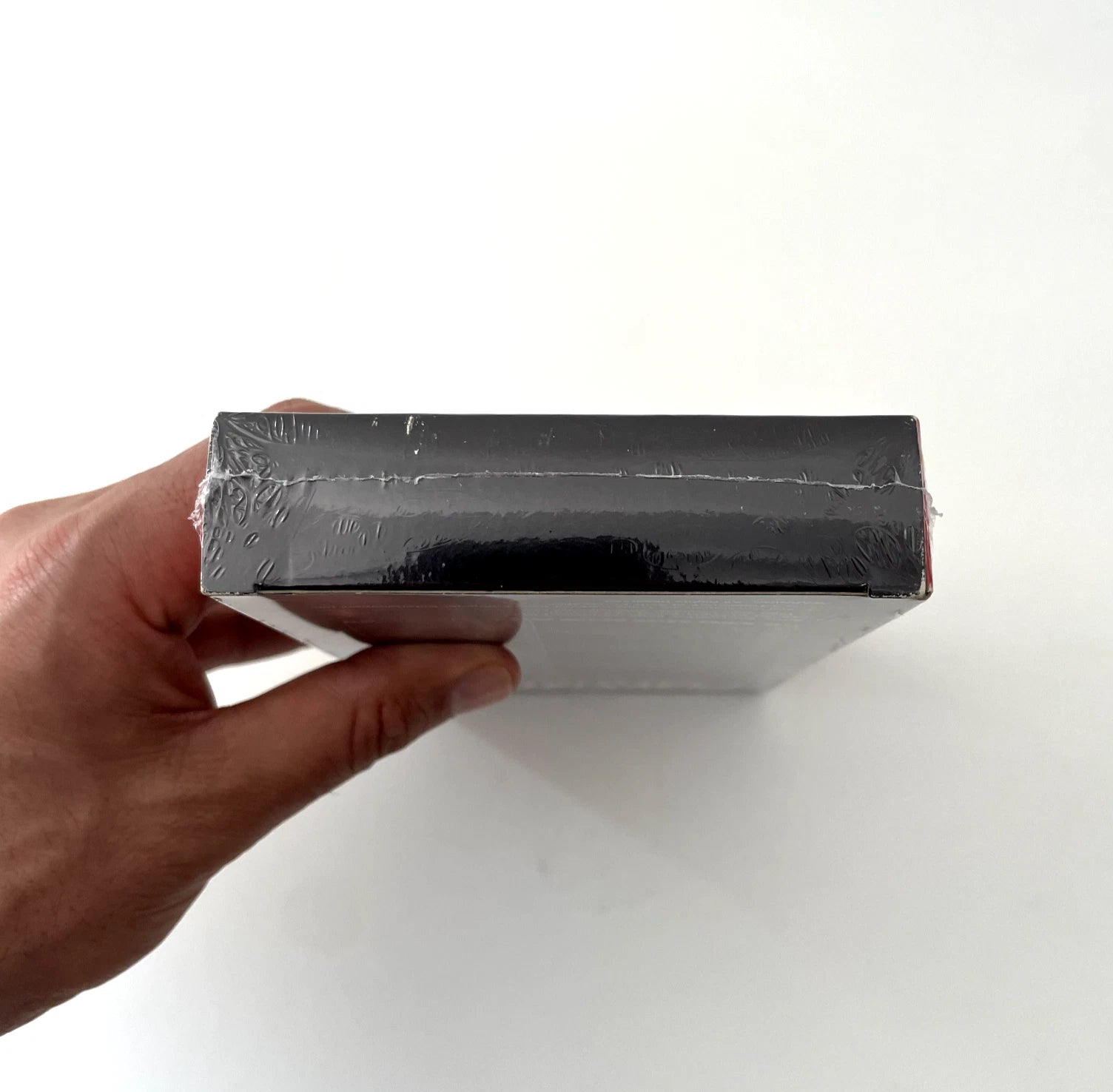 Hand holding a black rectangular object against a white background