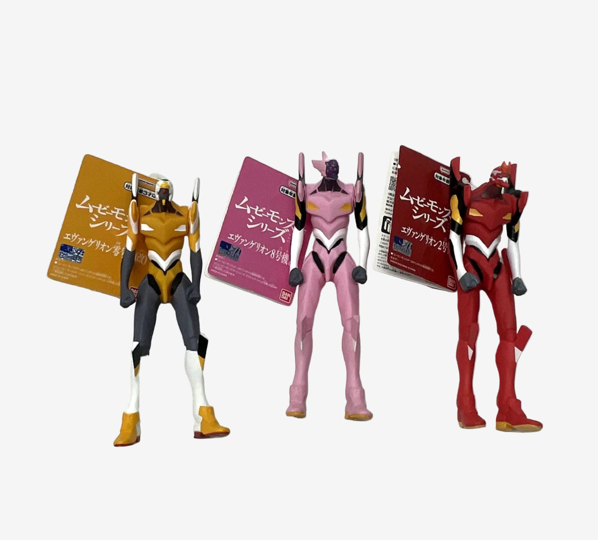 Three action figures of Evangelion characters with their packaging on a white background