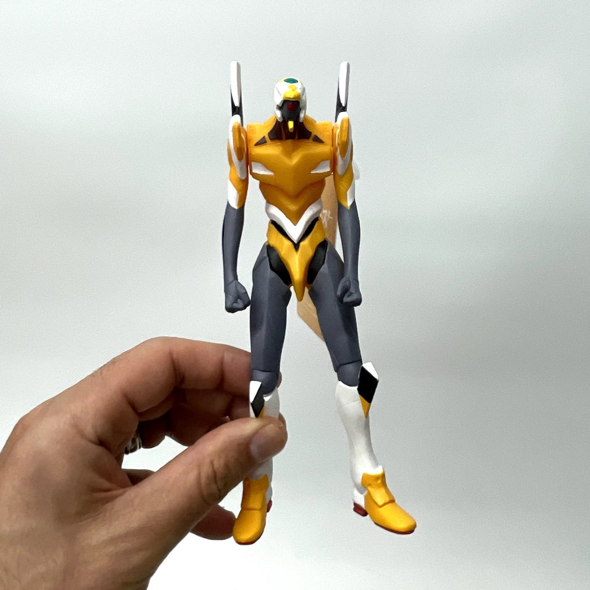 Hand holding a robot action figure against a plain background