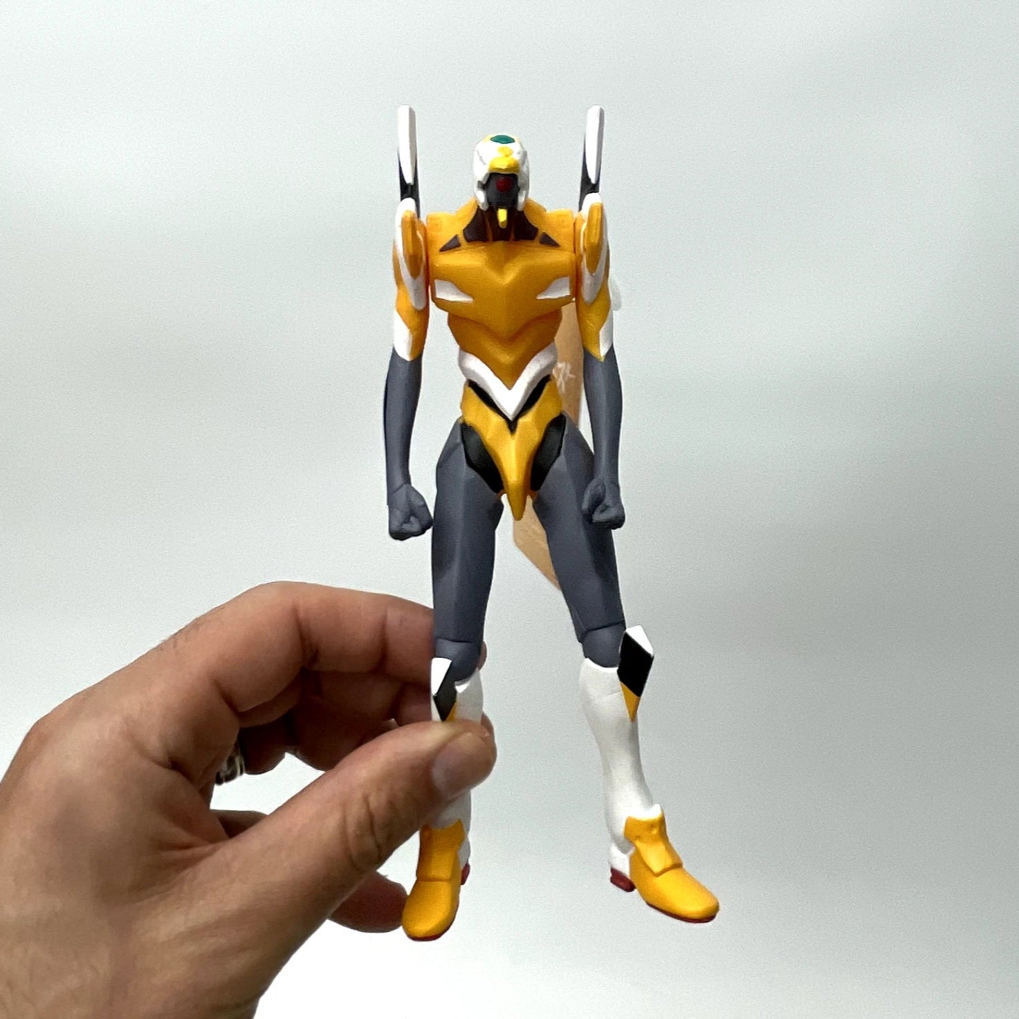 Hand holding a robot action figure against a plain background