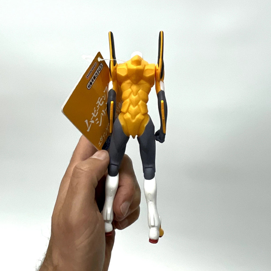 Hand holding a yellow and black action figure with a white background