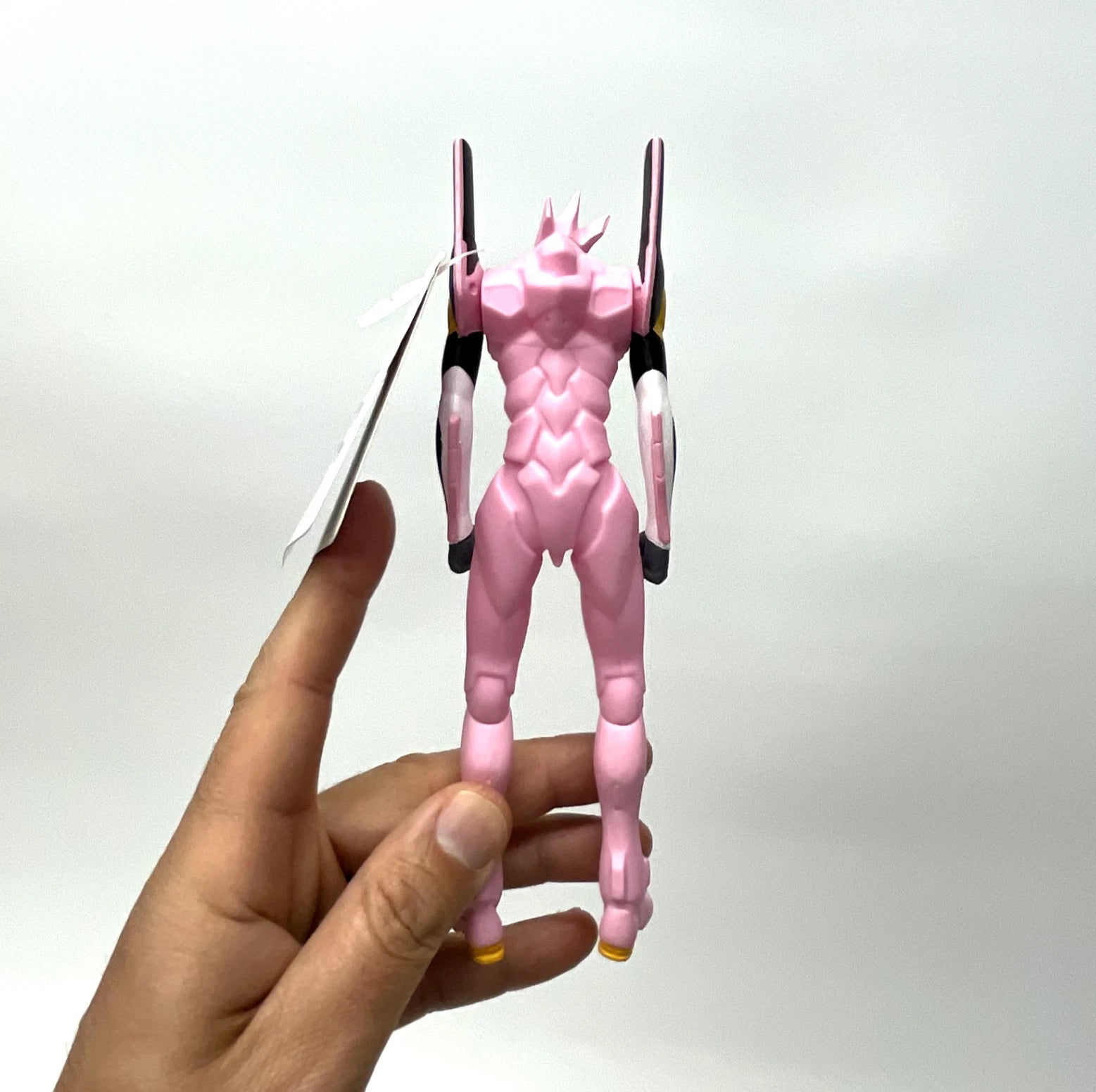 Hand holding a pink and black action figure against a white background
