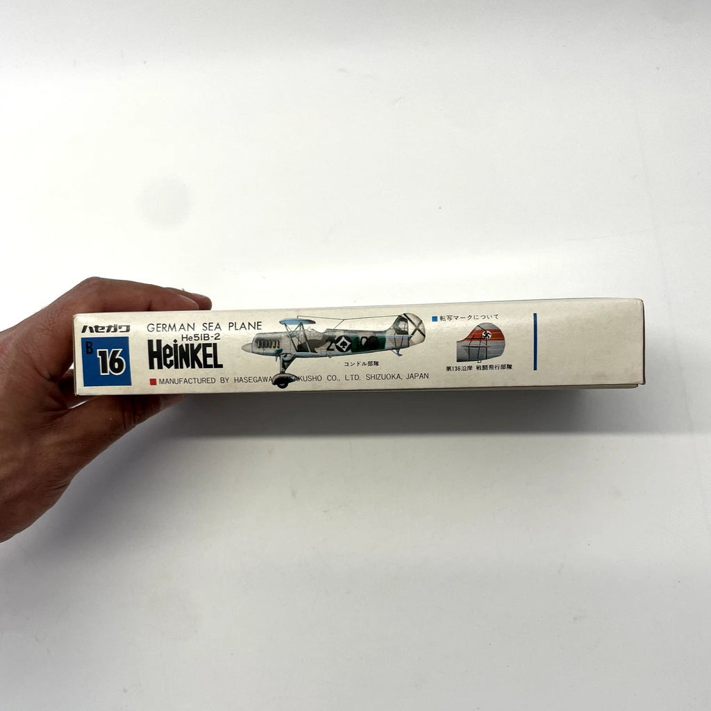 Model airplane box with Heinkel branding held by a hand on a white background